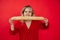 Hungry aggressive blond woman in red dress holding biting long french bread baguette in hands on red isolated background