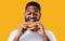 Hungry Black Guy Biting Burger Standing Over Yellow Studio Background