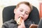 A Hungry boy eating a hot dog at home sit while playing with the smartphone.Close-up