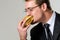 Hungry businessman eating hamburger