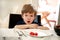 Hungry child sitting in chair at table in kitchen and waiting for meal and lunch. Boy is curious what he will get for meal.