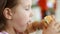 Hungry cute baby girl eating burger in fastfood cafe. Child eats food hamburger closeup