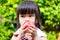 Hungry cute girl eats a red apple. Headshot of Asian children gnaw fruit. Child held it with both hands so that she could bite.