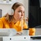 Hungry female gamer eats noodles Chinese dish with chopsticks at home interior using desktop pc computer during