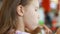 Hungry funny baby girl eating burger in fastfood cafe. Child eats food closeup