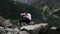 Hungry funny businessman eats spaghetti with hands when sitting on a stone near a lake in the mountains