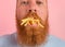 Hungry man with beard and tattoos eats fried potatoes