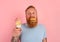 Hungry man with beard and tattoos is undecided if to eat an icecream or a sandwich with hamburger