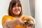 Hungry overweight woman smiling and holding hamburger and sitting in the bedroom, her very happy and enjoy to eat fast food.