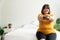 Hungry overweight woman smiling and holding hamburger and sitting in the bedroom, her very happy and enjoy to eat fast food. Conce