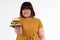 Hungry overweight young Asian woman holding hamburger on isolated background, Her hungry all time and overeat, gluttony and binge