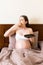 Hungry pregnant woman is eating tasty desserts staying in bed at home. Enjoying sweet food during pregnancy concept