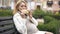 Hungry pregnant woman enjoying delicious burger sitting on bench in park