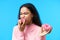 Hungry pretty girl eating donuts isolated over blue background