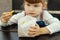 A hungry, pretty little girl holds a paper bag of French fries in her hand at a fast food cafe. Portrait of a happy child sitting