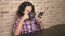 Hungry teen boy eats in the kitchen and uses a smartphone.