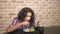 Hungry teen boy eats in the kitchen and uses a smartphone.