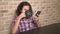 Hungry teen boy eats in the kitchen and uses a smartphone.