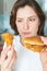 Hungry woman chooses what to eat first. Harmful cheeseburger and chicken wing in female hands