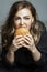 Hungry woman eats a hamburger. Beautiful blonde in gray pajamas. Junk food and unhealthy. Gray background. Vertical. Close-up