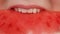 A hungry young girl with perfectly even white teeth and red lipstick bites a slice of bright, juicy watermelon and