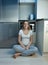 Hungry young woman in pajamas sitting on floor at refrigerator