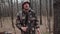 Hunter forest ranger dressed in a camouflage suit tells something to camera. Strange correspondent reporter with