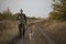 Hunter with Russian spaniel dog walking on the dirt road.