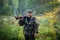 Hunter with a shotgun in his hands walking on a foggy morning on a rural road in a forest