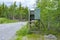 hunter stand near the road at the edge of the summer green forest with good view on trees and sky with clouds