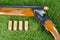 Hunting rifle next to three bullets on a green lawn