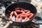 Hunting sausages in pan on fire in summer