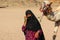 HURGHADA, EGYPT - Apr 24 2015: The old woman-cameleer from Bedouin village in Sahara desert with her camel, Egypt, HURGHADA on Apr