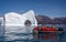 Hurtigruten`s MS Fridtjof Nansen expedition  cruise ship seen through an arch in a gigantic iceberg with zodiac of intrepid touris