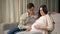 Husband caresses pregnant stomach of wife sitting on sofa