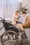 husband with disability and wife playing chess in bedroom with wheelchair