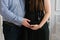 Husband holds his hand on the belly of a pregnant woman in a black dress close-up. Expectant parents expecting a baby