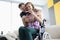 Husband hugs his wife in wheelchair by shoulders with positive pregnancy test