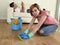 Husband resting on couch while wife cleaning doing housework in chauvinism concept