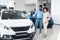 Husband Showing Wife New Auto Standing In Showroom, Full Length