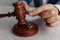 Husband signing divorce contract. Man`s hand, gavel of judge and rings close-up. Divorce concept