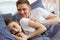 Husband wakes his beloved beautiful wife in the morning in bed. Couple in bedroom, loving family