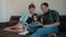 Husband, wife and child together read a book on the couch.