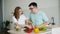 Husband and wife cooking salad together cutting vegetables in kitchen at home