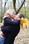 Husband and wife embrace and kiss in autumn forest.