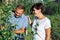 A husband and wife inspect the fruit harvest in their garden on a sunny summer day.