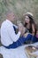 husband and wife on a romantic date on a picnic drinking wine. happy couple. brunette and bald man in the field.