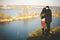 Husband and wife on the shore of the lake with rocky shores, early spring. Silhouettes of lovers who go into the water on the back