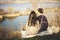 Husband and wife on the shore of the lake with rocky shores, early spring. Silhouettes of lovers who go into the water on the back