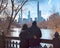 Husband and wife standing on the Old Bridge viewing the skyline of New York City across the Bank Rock Bay.